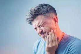 A man experiencing severe tooth pain and holding his jaw.