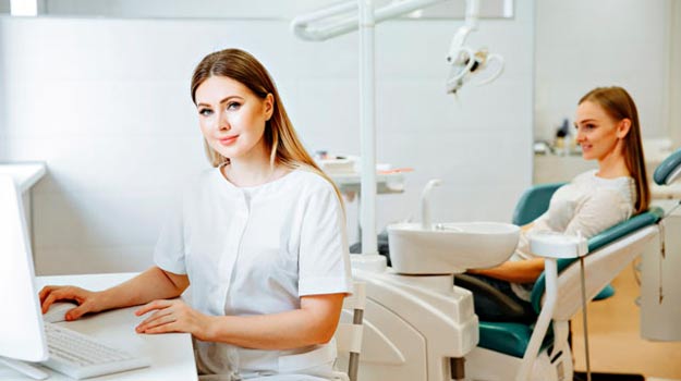A Portrait Of Female Dentist Working On A Computer And Slight Look Towards The Camera