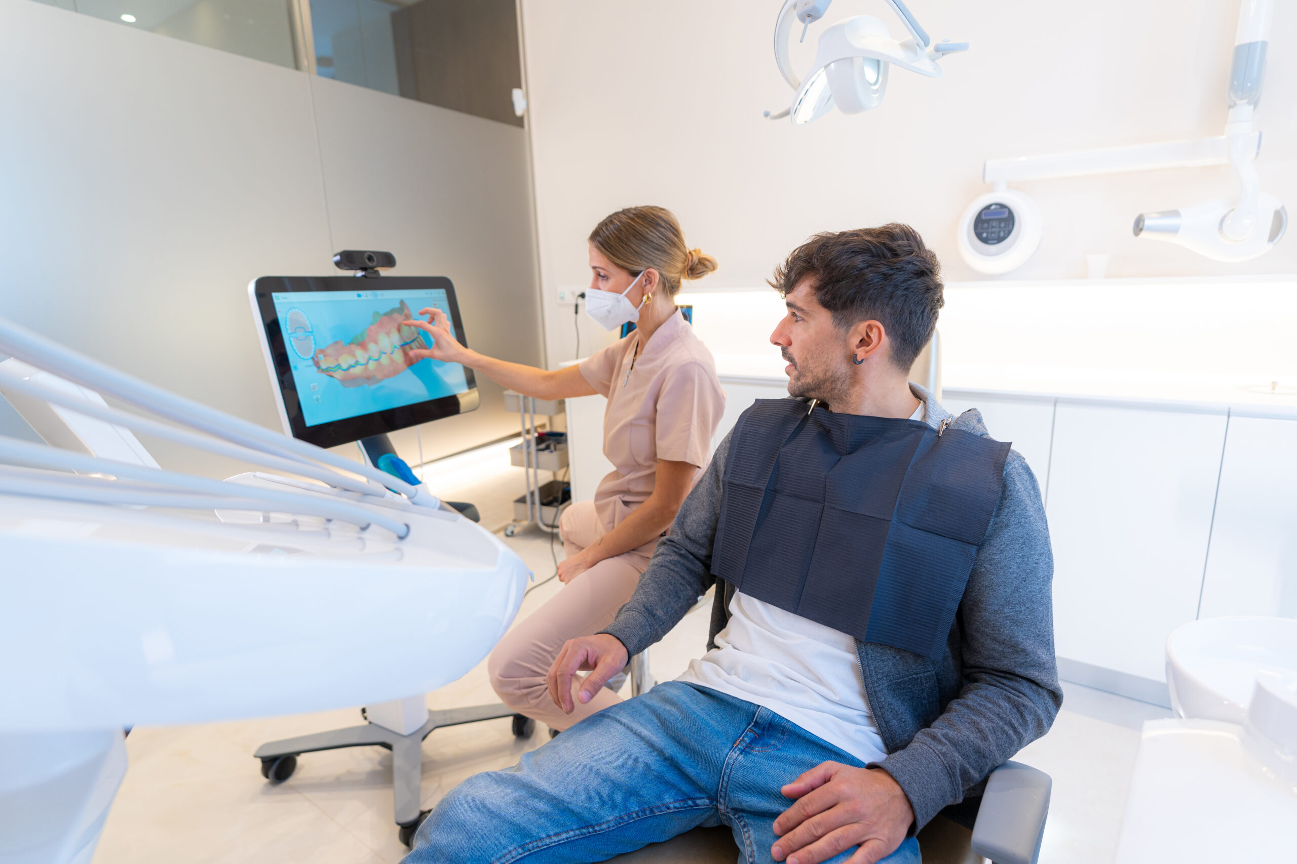 Dentist using modern technology to explain the dental procedure to a man sitting on the clinic
