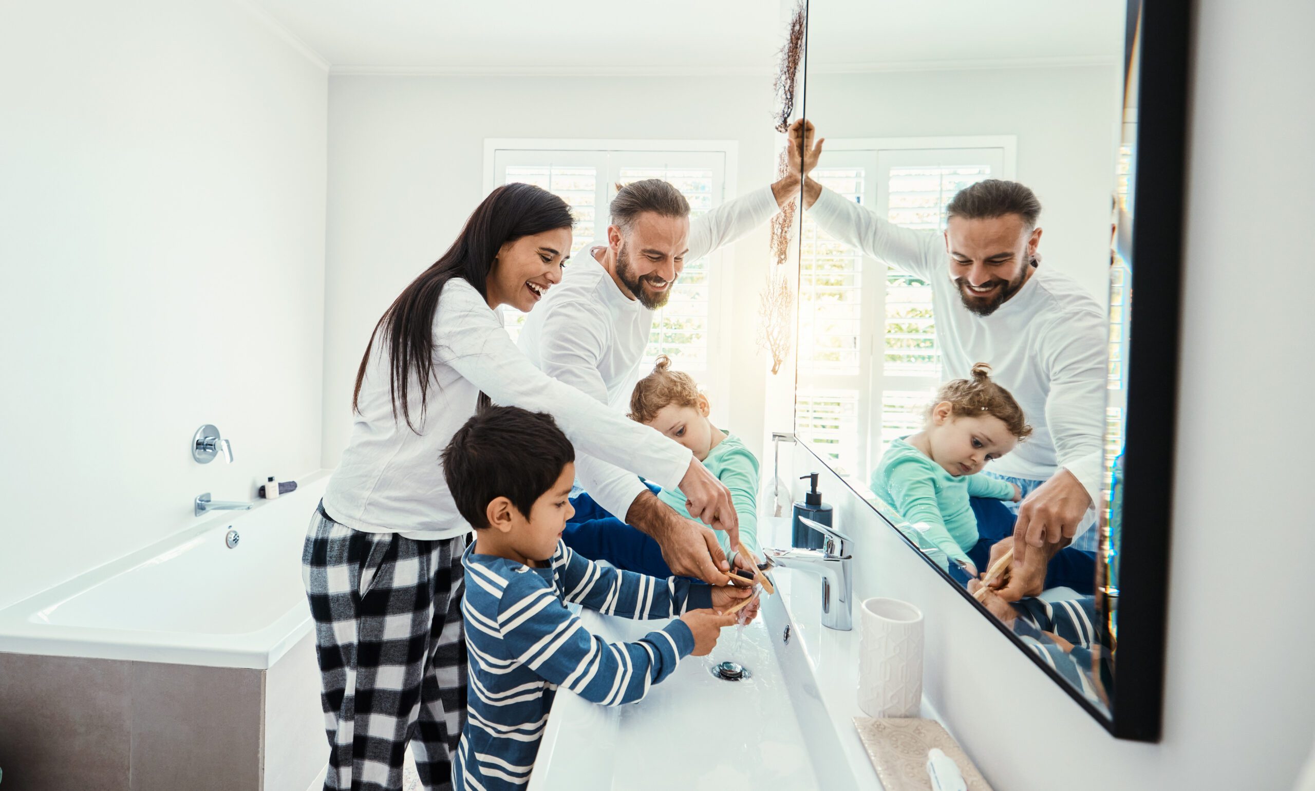 Family, washing hands and bathroom with a mom, father and children with hygiene care in morning. Mother, kids and dad together with love, support and youth in a home doing self care at a sink.