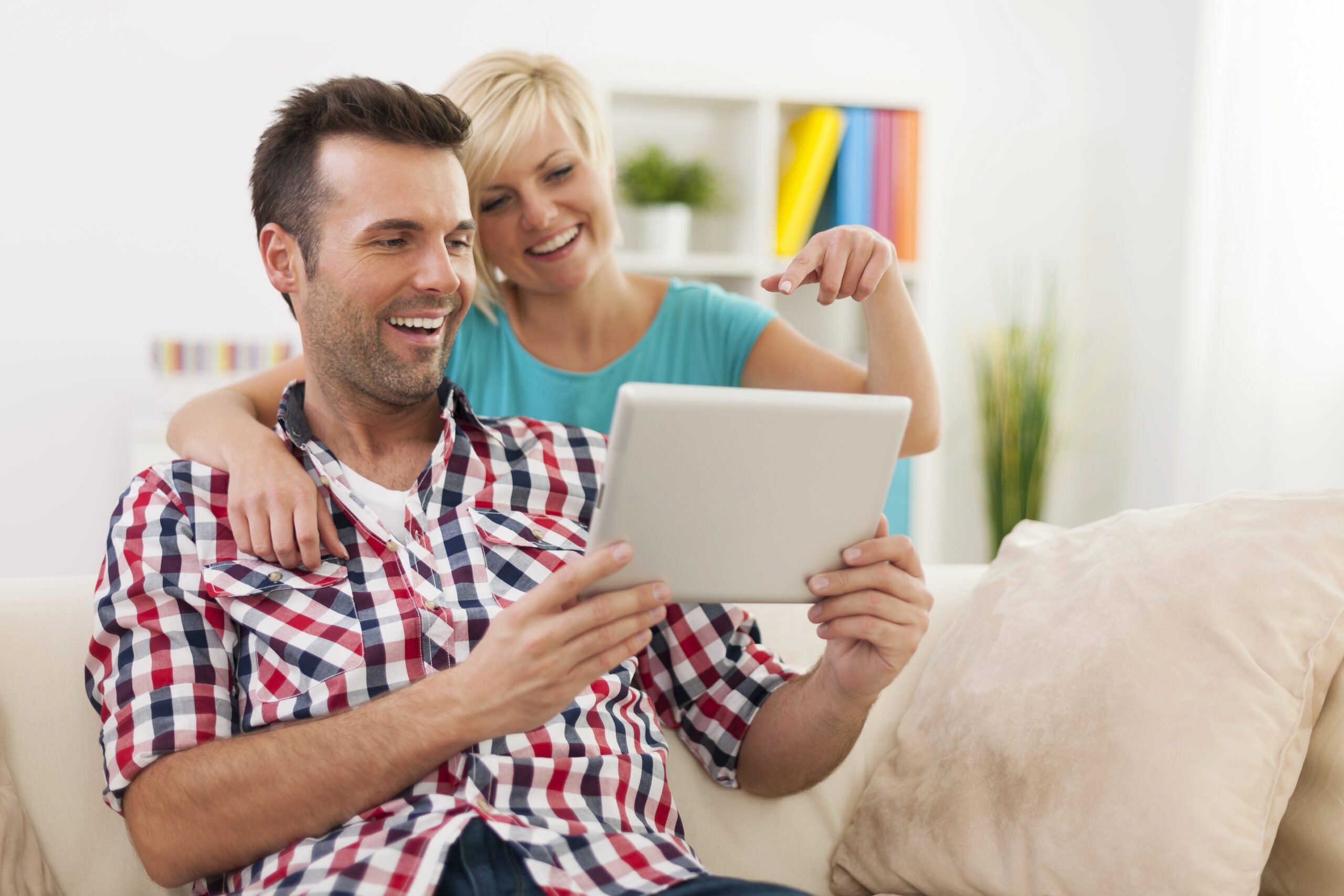Happy couple using digital tablet at home