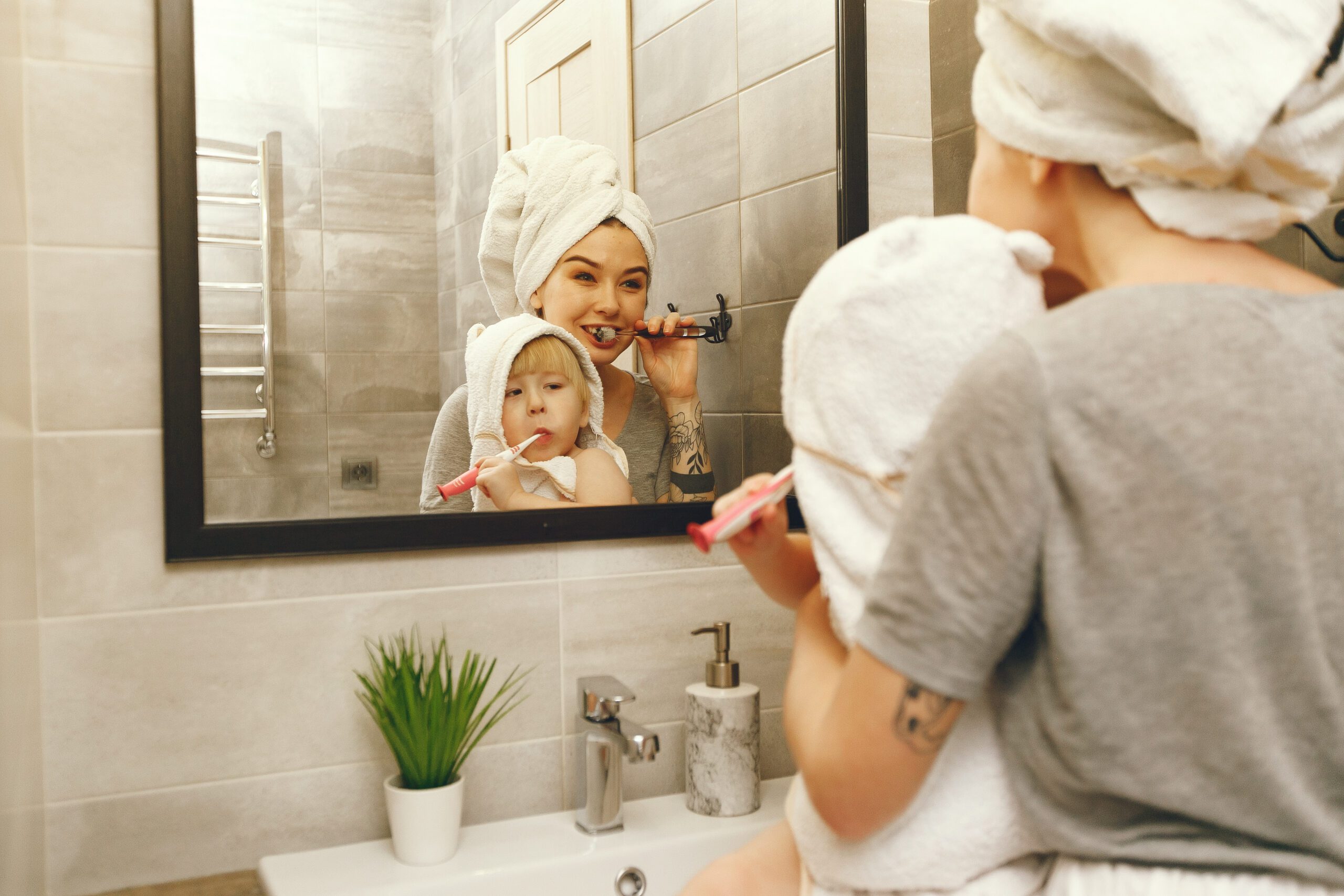 Family in a bathroom. Beautiful mother with little son. Little boy brush his teeth.