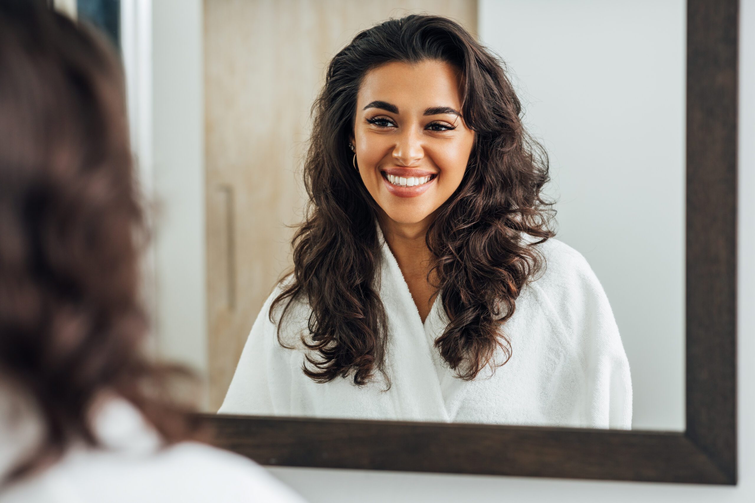 smiling-young-woman-looking-mirror