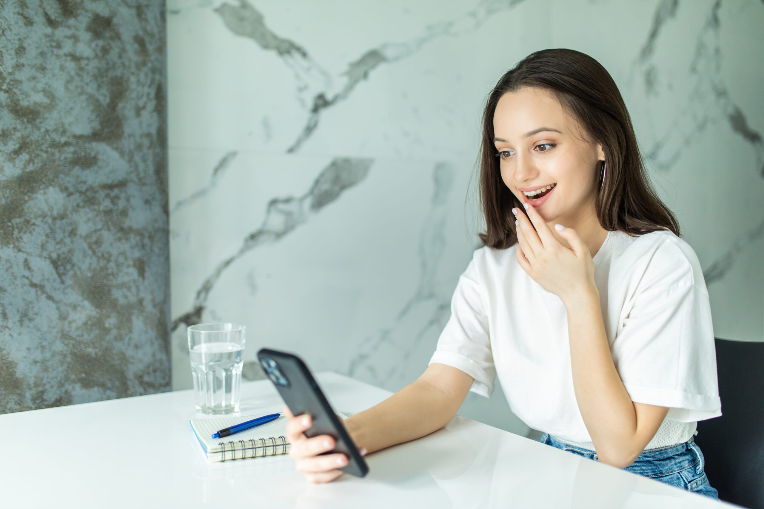 Smiling woman using smart phone in kitchen. Woman scroll through the social network